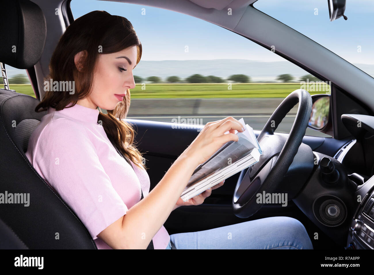 Seitenansicht einer schönen Frau mit Buch beim Fahren Auto Stockfoto