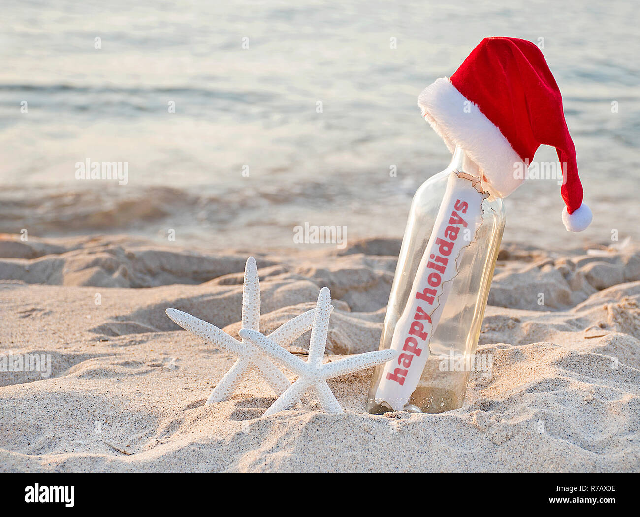 Santa Hut auf Nachricht in einer Flasche mit Paar weiße Seesterne in Sand und schöne Feiertage Gruß Stockfoto