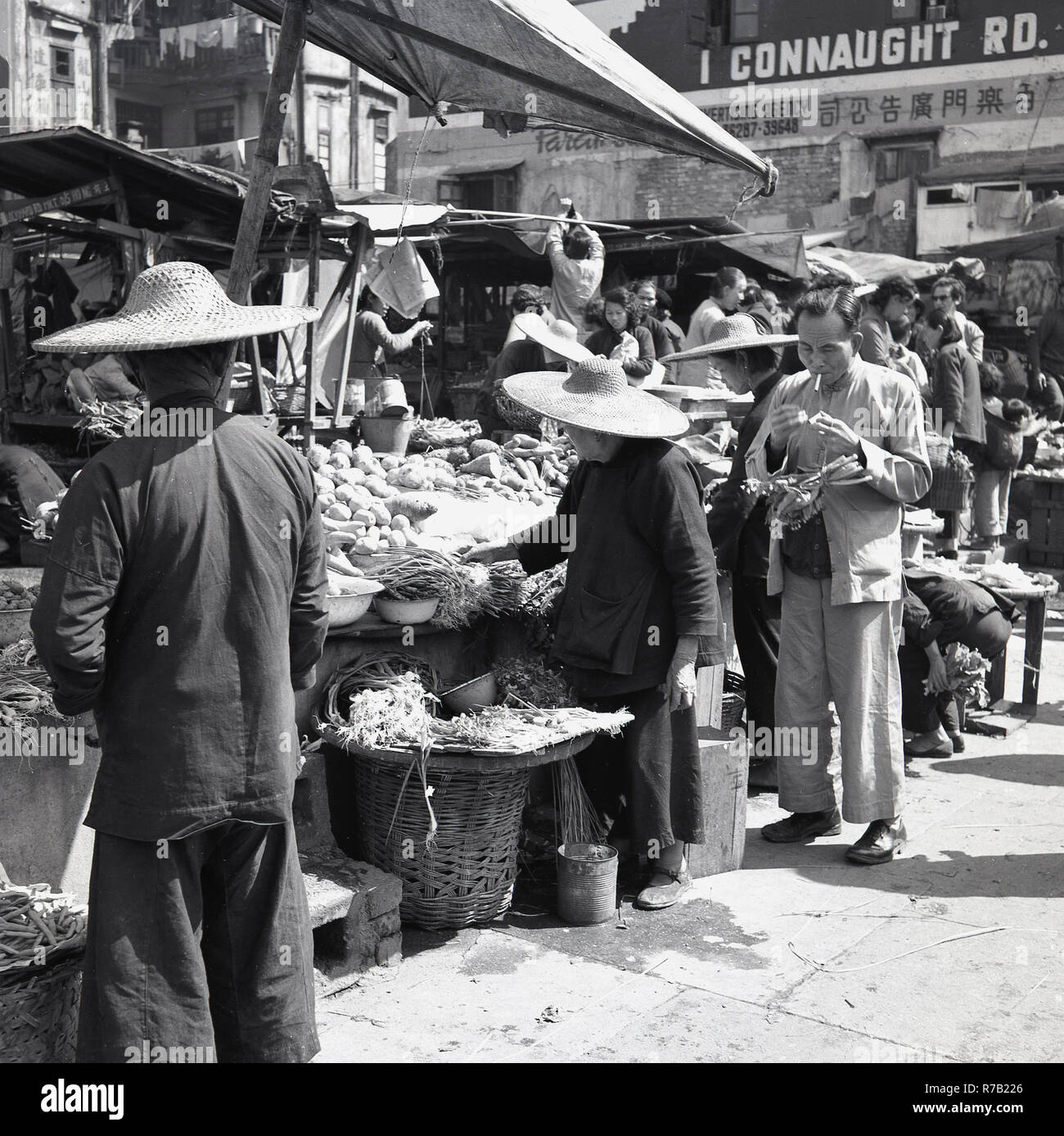 1950, Hong Kong, 1 Connaught Rd, lokale Chinesen in traditioneller Kleidung und Hüte Shopping bei einem Open-Air-Markt im Freien in alten Hong Kong abgewürgt. Stockfoto