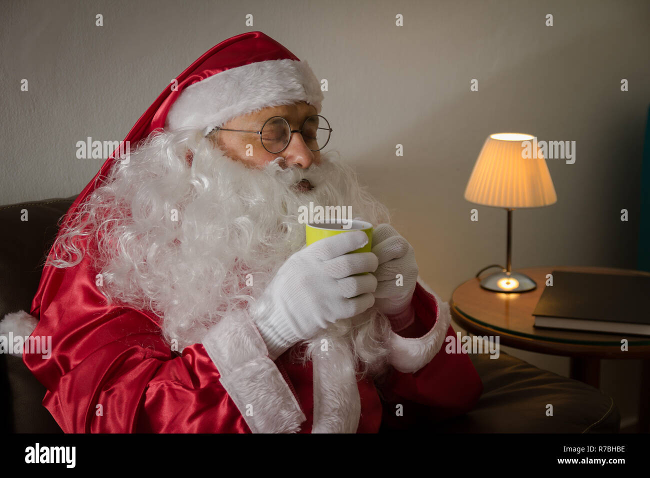 Seitlich von Santa Claus (oder Kris Kringle) Entspannung im Sofa zu Hause genießen eine Tasse Kaffee oder Tee. Stockfoto