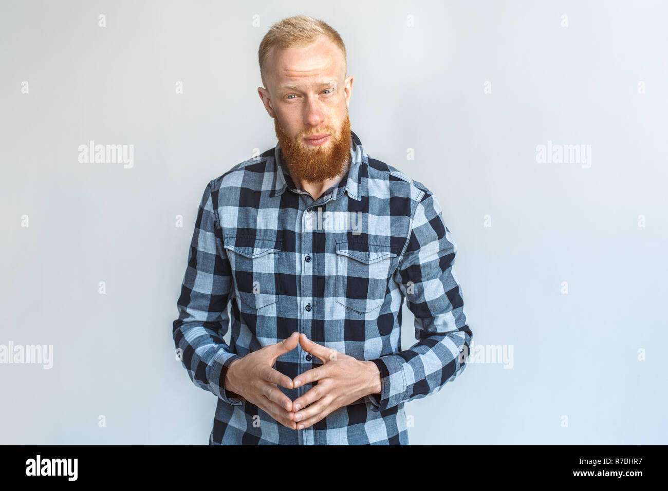 Freestyle. Reifer Mann stehend auf Grau halten Hände steepled suchen Kamera isoliert neugierig Stockfoto