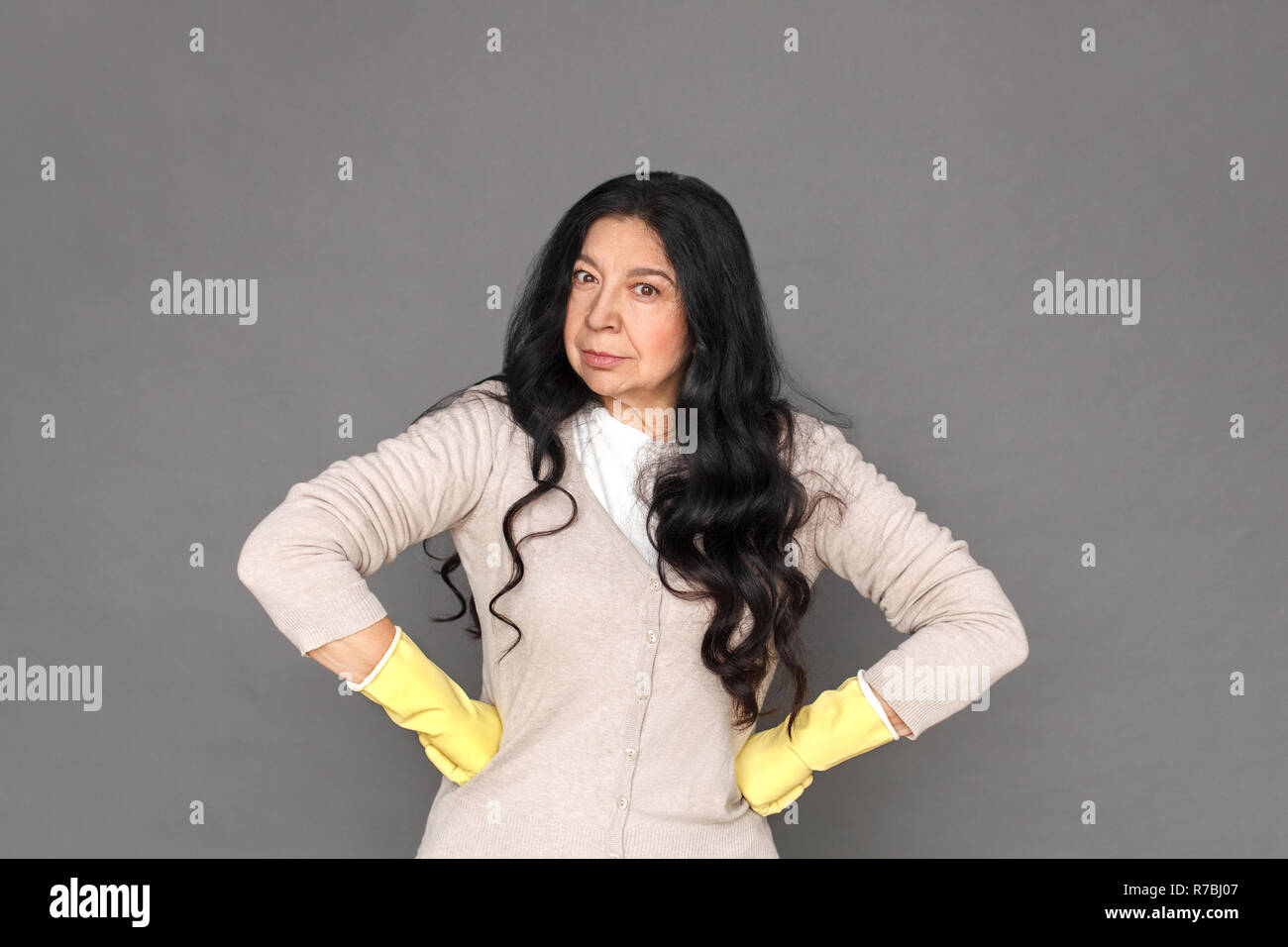 Freestyle. Reife lady in Gummihandschuhe auf grau Hände isoliert stehen auf den Hüften schwere Stockfoto
