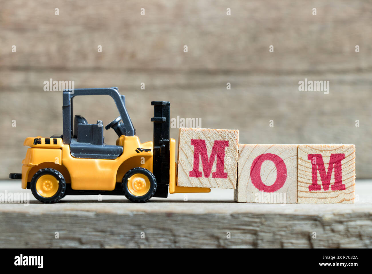 Spielzeug gelb Gabelstapler halten schreiben Block M zu Wort Mama auf Holz Hintergrund komplett (Konzept für Muttertag) Stockfoto