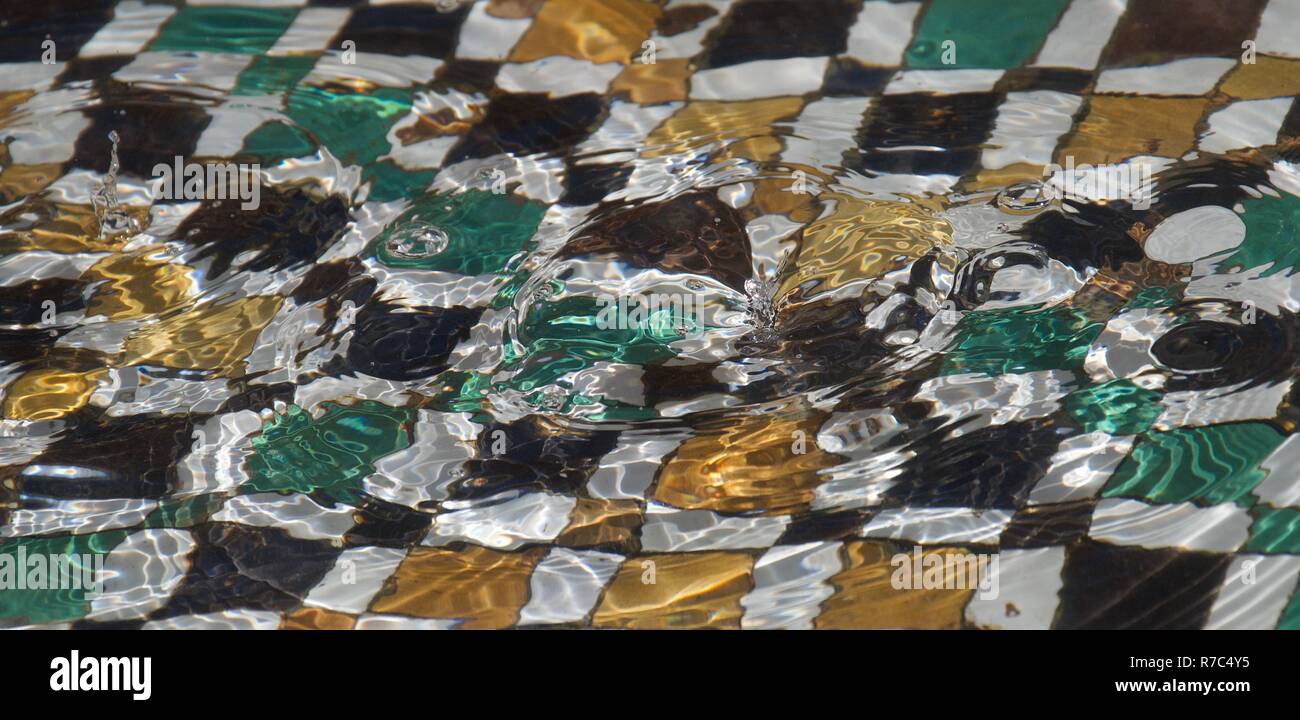 Wasser bildet Tröpfchen drastisch und Wellen in einem Fliesen- afrikanischen Brunnen Stockfoto