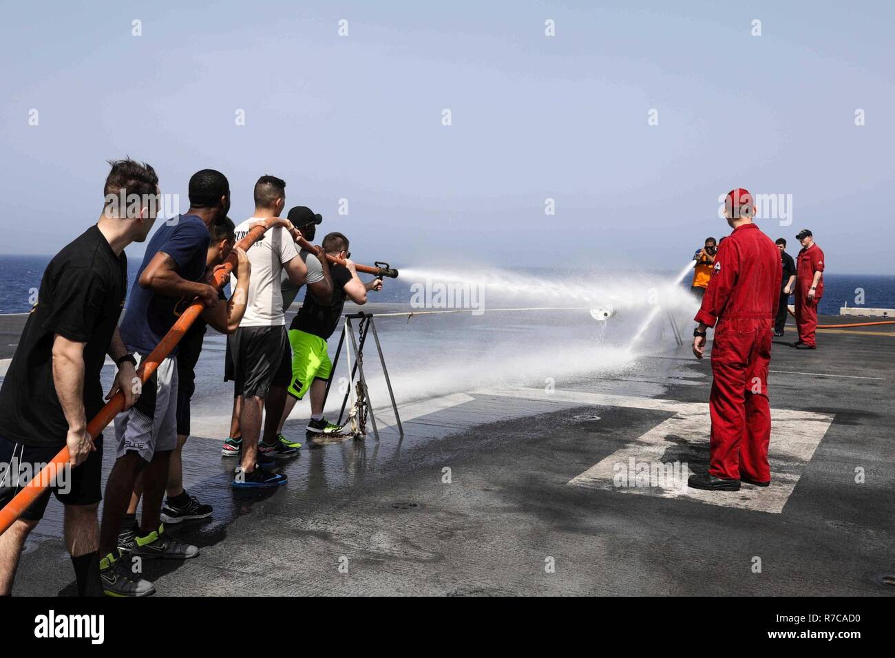 5. US-Flotte BEREICH VON OPERATIONEN (5. Mai 2017) Matrosen und Marines im Feuer Schlauch Ereignis während der Schadensbegrenzung Olympics konkurrieren während einer Stahl Picknick am Strand auf dem Flugdeck des Amphibious Assault ship USS Bataan (LL 5). Das Schiff und seine Gruppe bereit sind in den USA 5 Flotte Bereich für Maßnahmen zur Erhöhung der Sicherheit des Seeverkehrs auf die Verbündeten und Partnern zu beruhigen bereitgestellt, und der Freiheit der Schiffahrt und des freien Handels in der Region erhalten. Stockfoto