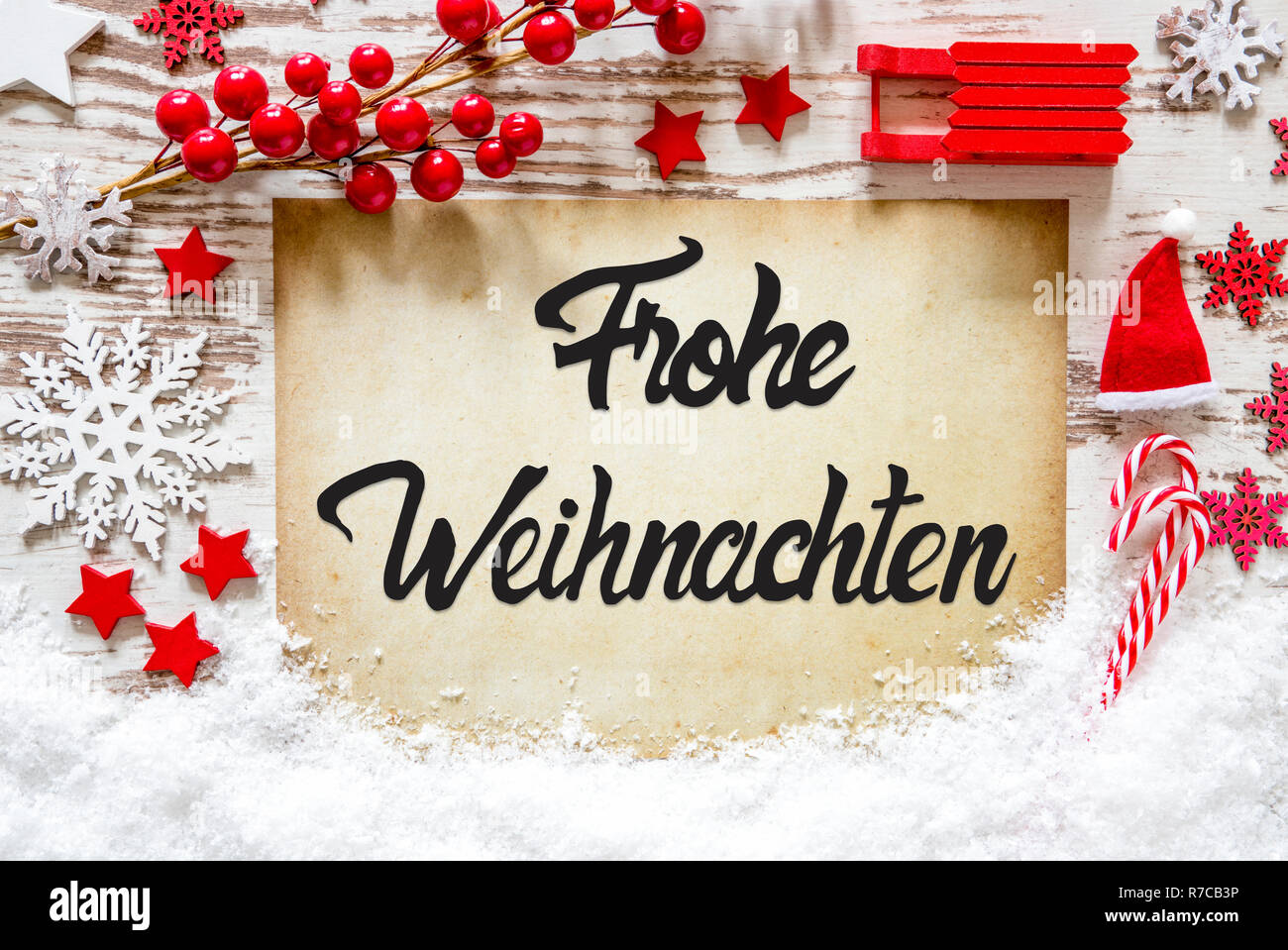 Papier mit Deutschen Kalligraphie Frohe Weihnachten bedeutet, frohe Weihnachten. Helles Rot Weihnachten Dekoration wie Schlitten, Sterne, Schneeflocke und Santa Hut mit Stockfoto