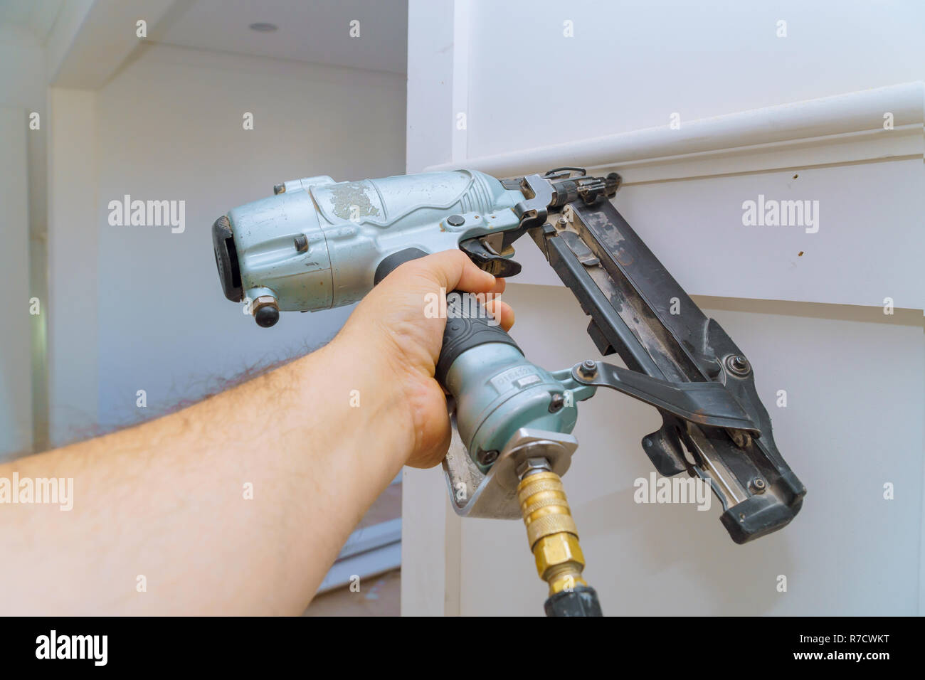 Installation von Leisten an der Wand von Fragment des Formteils, Ansicht von oben Tischler Brad mit bolzenschußgeräten Stockfoto