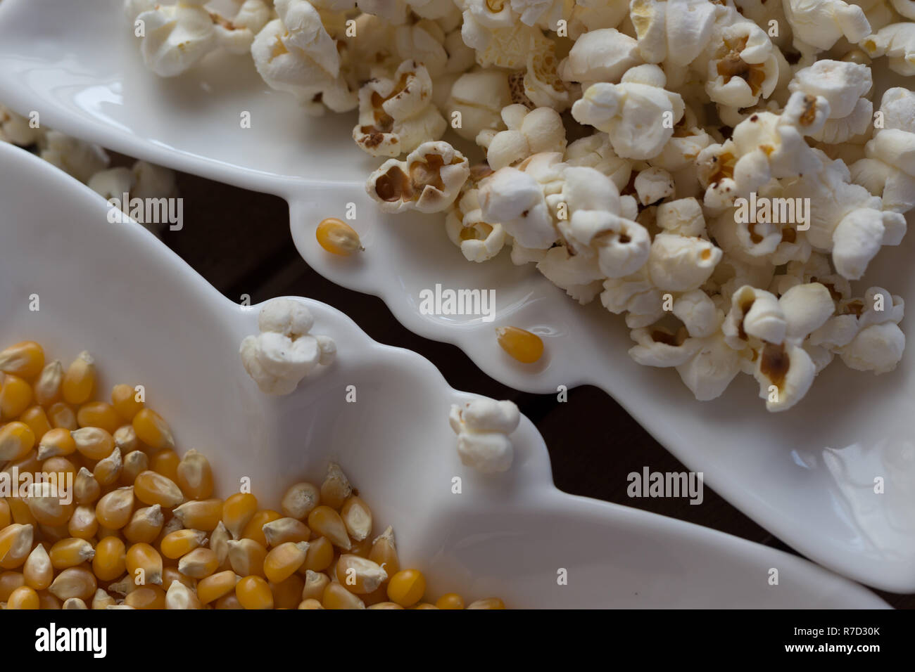Popcorn Popcorn und Körner auf weiße Platte auf hölzernen Hintergrund Stockfoto