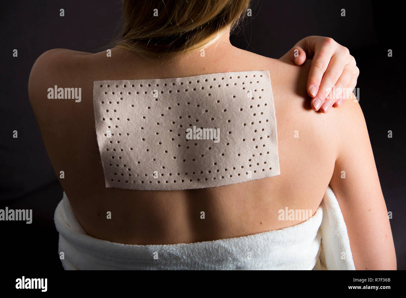 Junge Frau mit Rückenbeschwerden hat eine wärme Pflaster angewendet Stockfoto