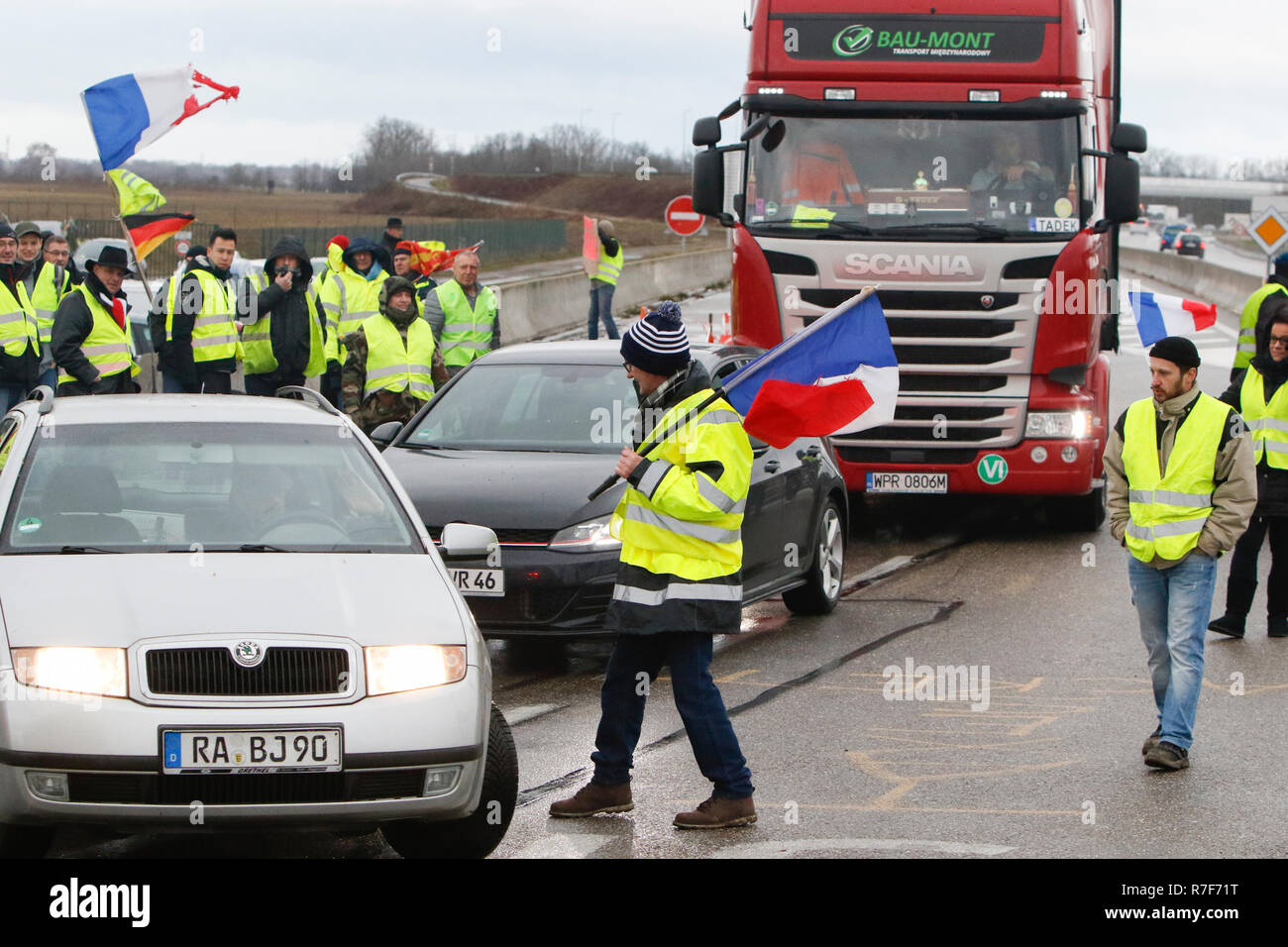 Roppenheim, Frankreich. 08 Dez, 2018. Autos fahren durch den Protest. Die Demonstranten jubeln, wenn die Treiber ihre Unterstützung zeigen. Rund 100 Französische gelbe Weste Aktivisten protestierten auf einer Straße in der Nähe der Französisch Deutsch Grenzübergang bei Roppenheim gegen die französische Regierung. Sie wurden von einigen Aktivistinnen aus der Deutschen rechten Gruppen unterstützt. Sie waren Teil der grösseren gelbe Weste Protestbewegung in Frankreich, die in den vergangenen 4 Wochen in ganz Frankreich protestiert. Quelle: Michael Debets/Pacific Press/Alamy leben Nachrichten Stockfoto