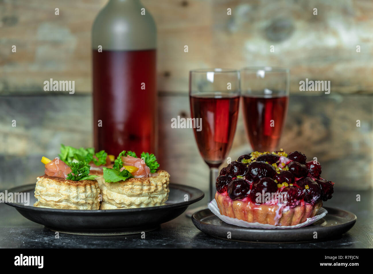 Süße Mahlzeit für zwei: Rotwein, Kuchen mit Puderzucker und Obst, French Pastetchen Stockfoto