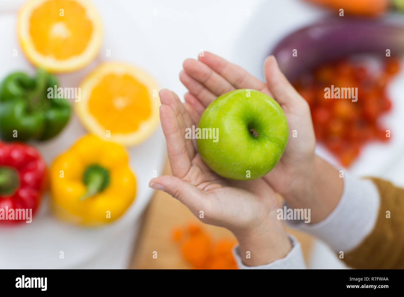 In der Nähe der weiblichen Händen hält Green Apple über Tabelle mit Gemüse Stockfoto