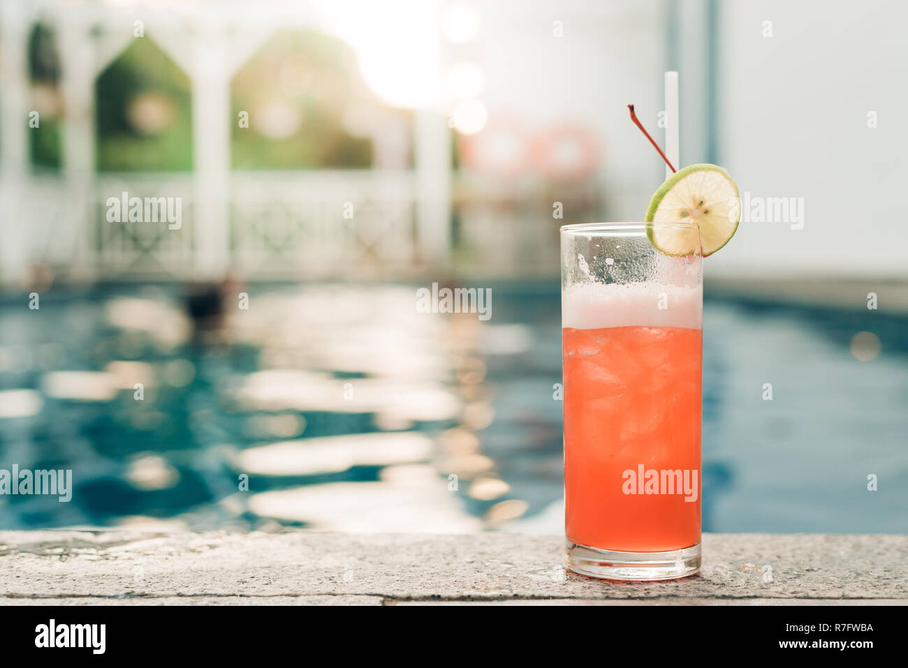 Cocktail am Rande des Schwimmbades. Red Cocktail mit einer Orange Slice auf dem Hintergrund der Pool. Vintage Effekt stil Bilder. Stockfoto