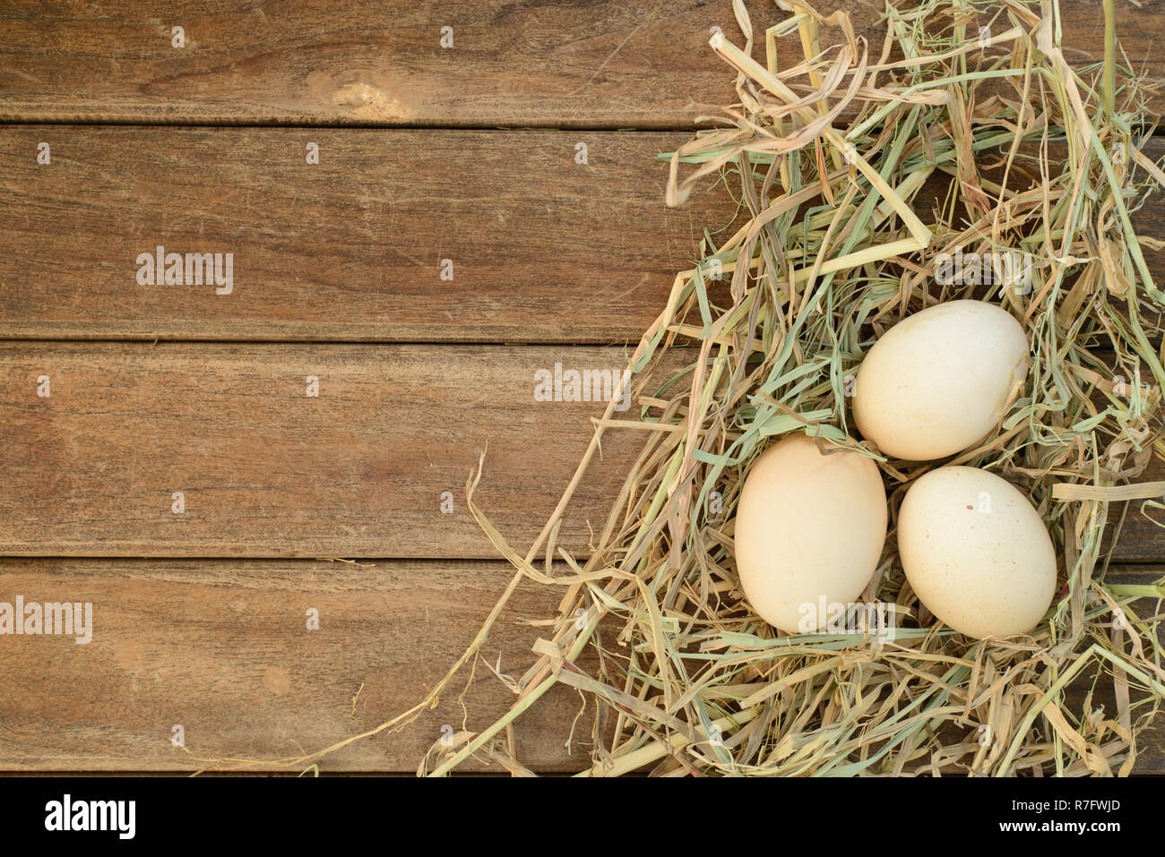 Ei im Nest Heu auf alten Holztisch Hintergrund, Ansicht von oben Stockfoto