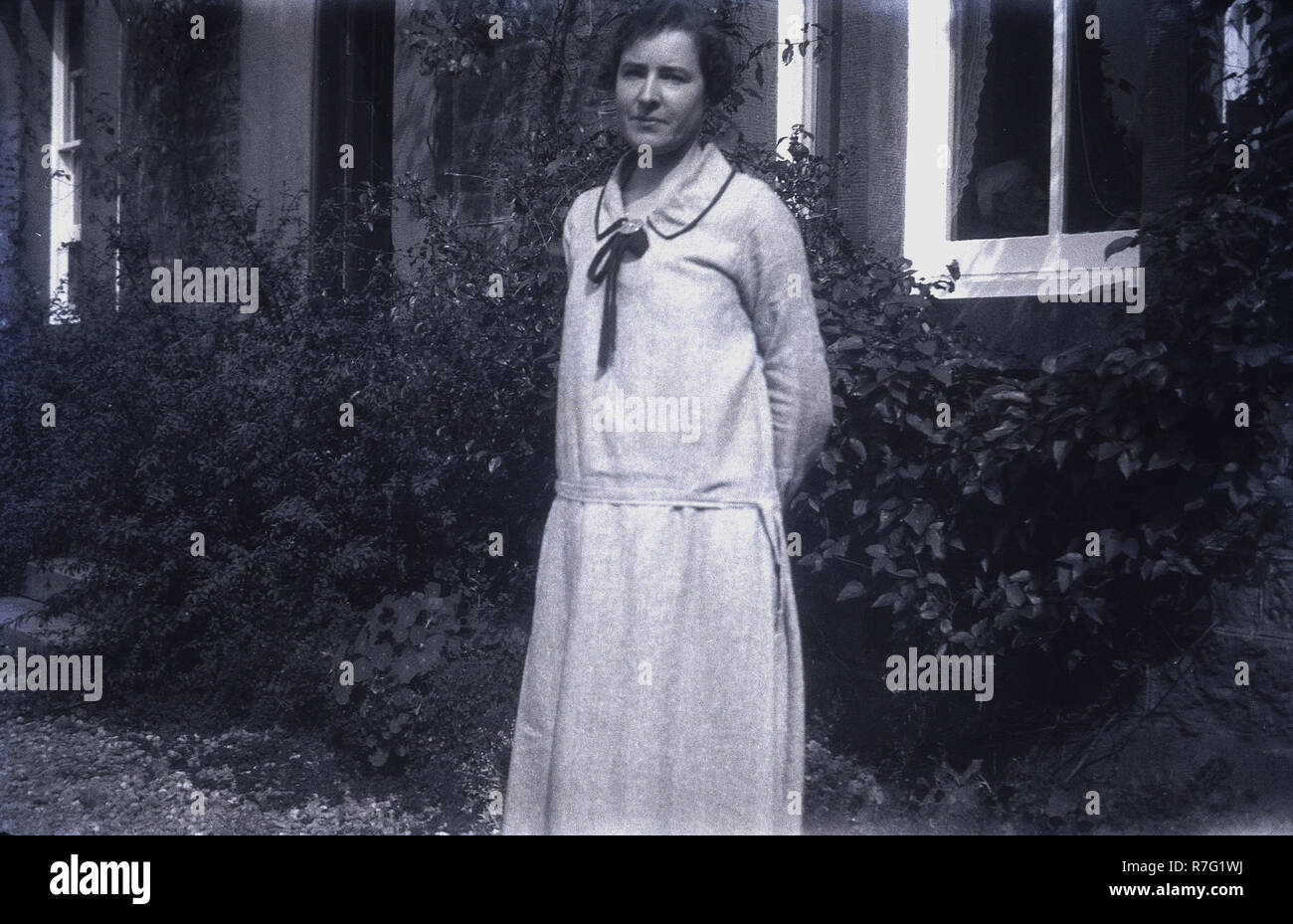 1930er Jahre, historische, eine Dame trägt ein Kleid typisch für die Epoche steht außerhalb eines Hauses Stockfoto