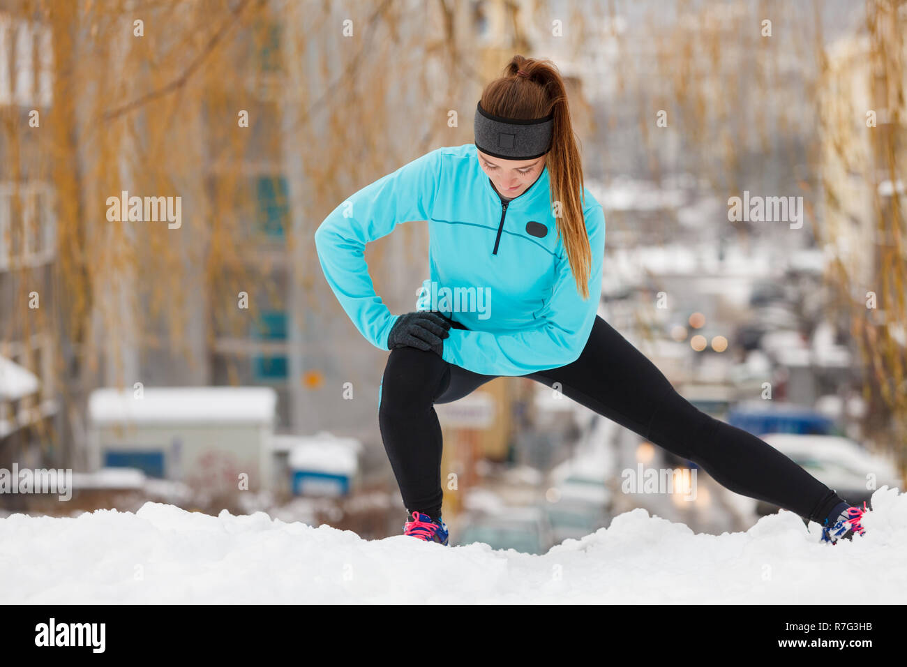 Mädchen Sportbekleidung tragen und Dehnübungen auf Schnee mit städtischen  Hintergrund. Winter Sport, Outdoor Fitness, Mode, Training, Gesundheit  Konzept Stockfotografie - Alamy