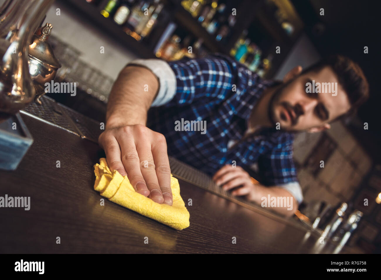 Junge Barkeeper stehen an der Theke Reinigung Oberfläche verschwommenen Hintergrund Stockfoto