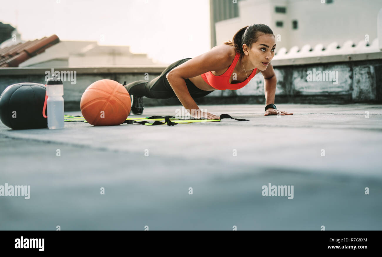 Sportlerin, Push-ups auf dem Dach mit medizinball und Basketball durch ihre Seite. Frau in fitness Verschleiß tun Workout auf der Terrasse. Stockfoto