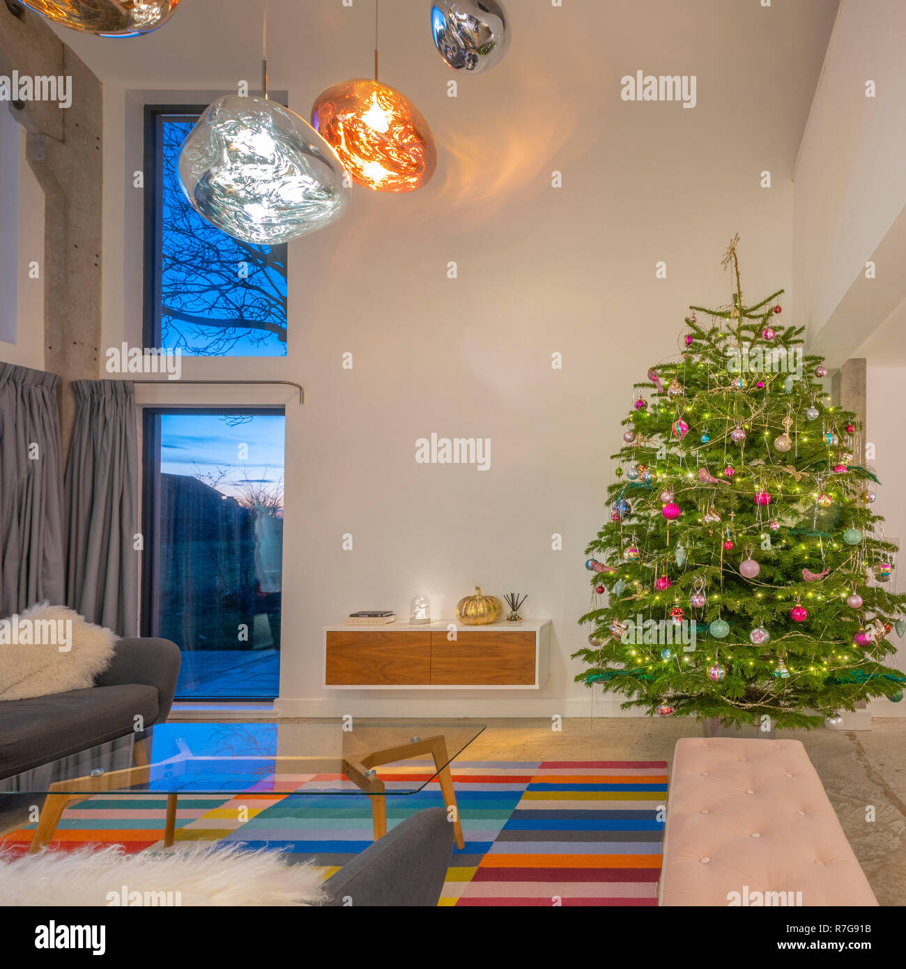 Moderne offene Wohn raum in Haus mit doppelter Höhe Windows, Tom Dixon Lichter und Weihnachtsbaum. Stockfoto