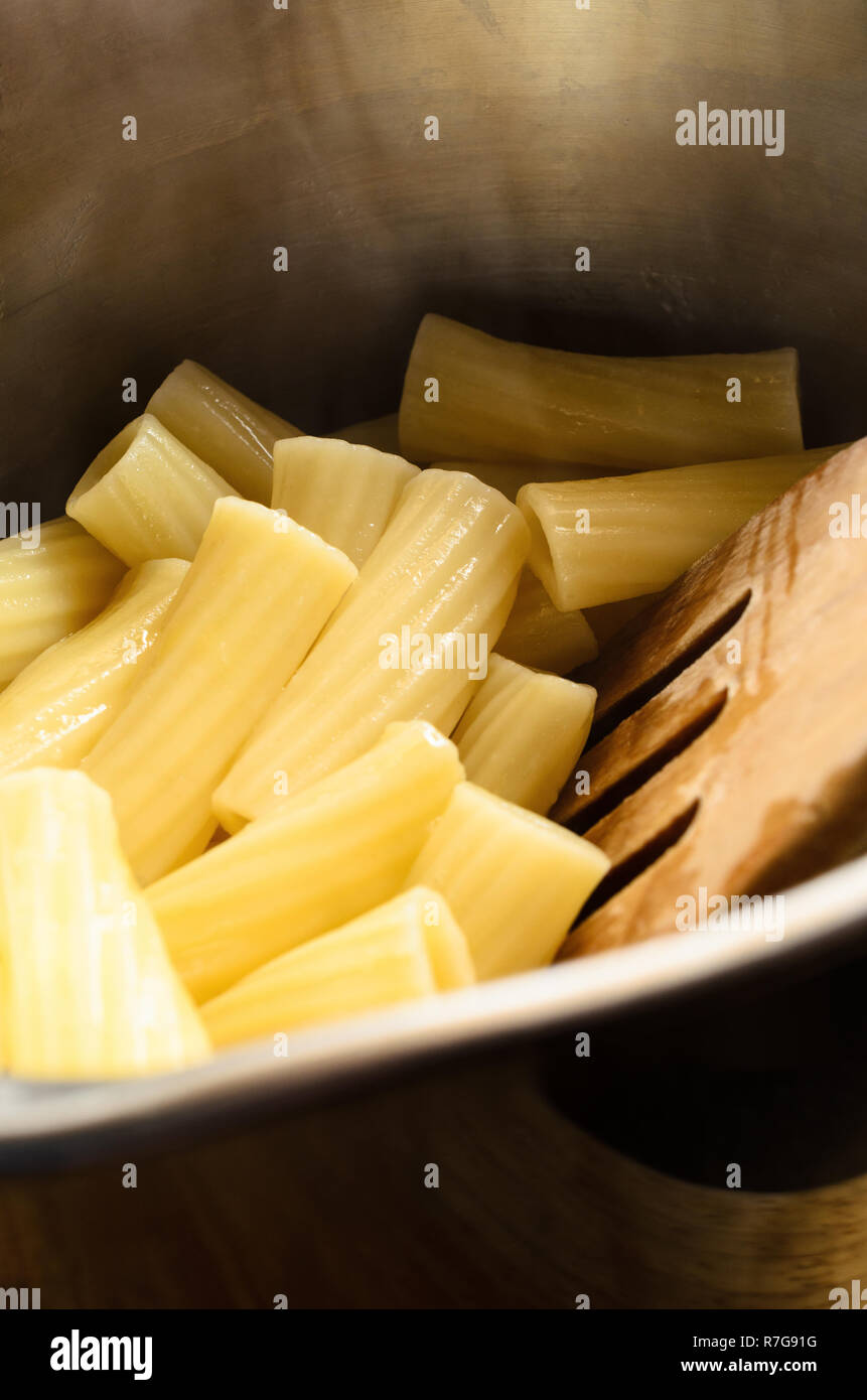 Frisch gekocht und abgetropft hot Pasta (Rigatoni) in Edelstahl Kochtopf mit Holzspachtel. Stockfoto