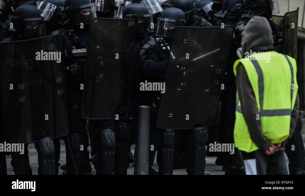 Paris, Frankreich, 8. Dezember 2018: Gelb (Gilets jaunes) Demonstrant vor der französischen Bereitschaftspolizei Offiziere steht während der Proteste gegen Livin Stockfoto