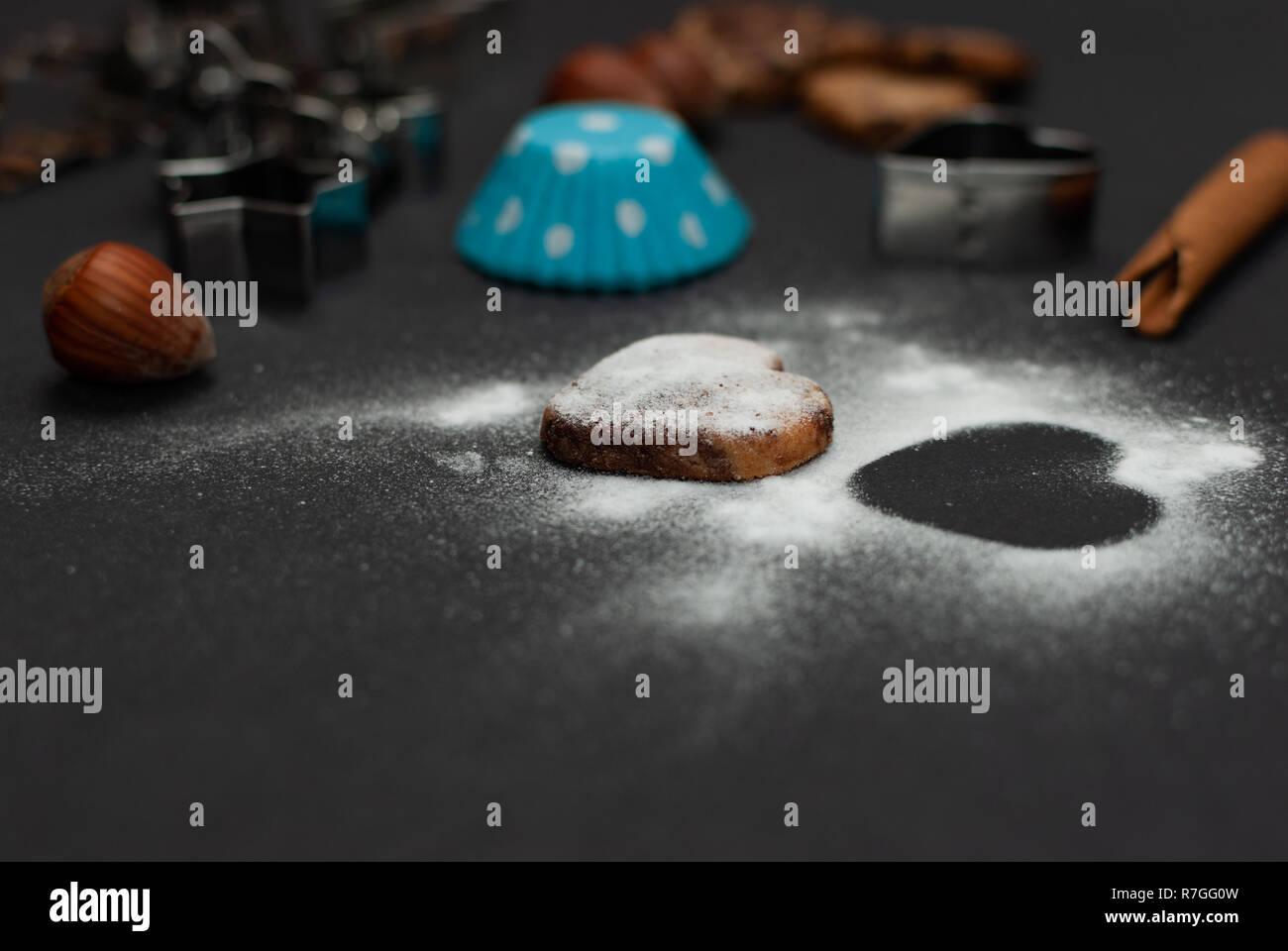 Cookies, Backformen, Schutzpapier, Zimt, Nüssen und süßem Zucker in Form eines Herzens auf schwarzem Hintergrund Stockfoto