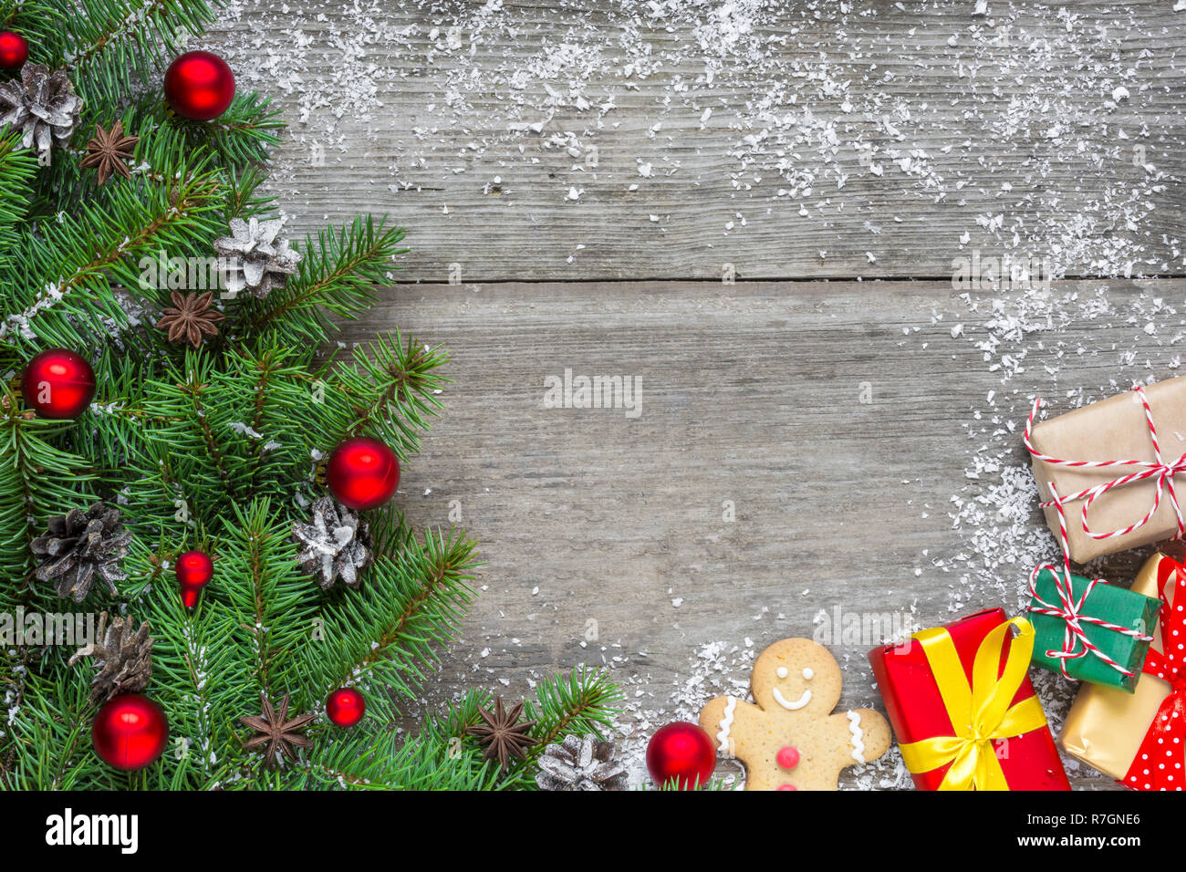 Weihnachten Hintergrund mit Fir Tree Branches, rot Dekorationen, Geschenkverpackungen und Tannenzapfen auf rustikalen Holztisch mit Schnee bedeckt. Flach. top Aussicht w Stockfoto