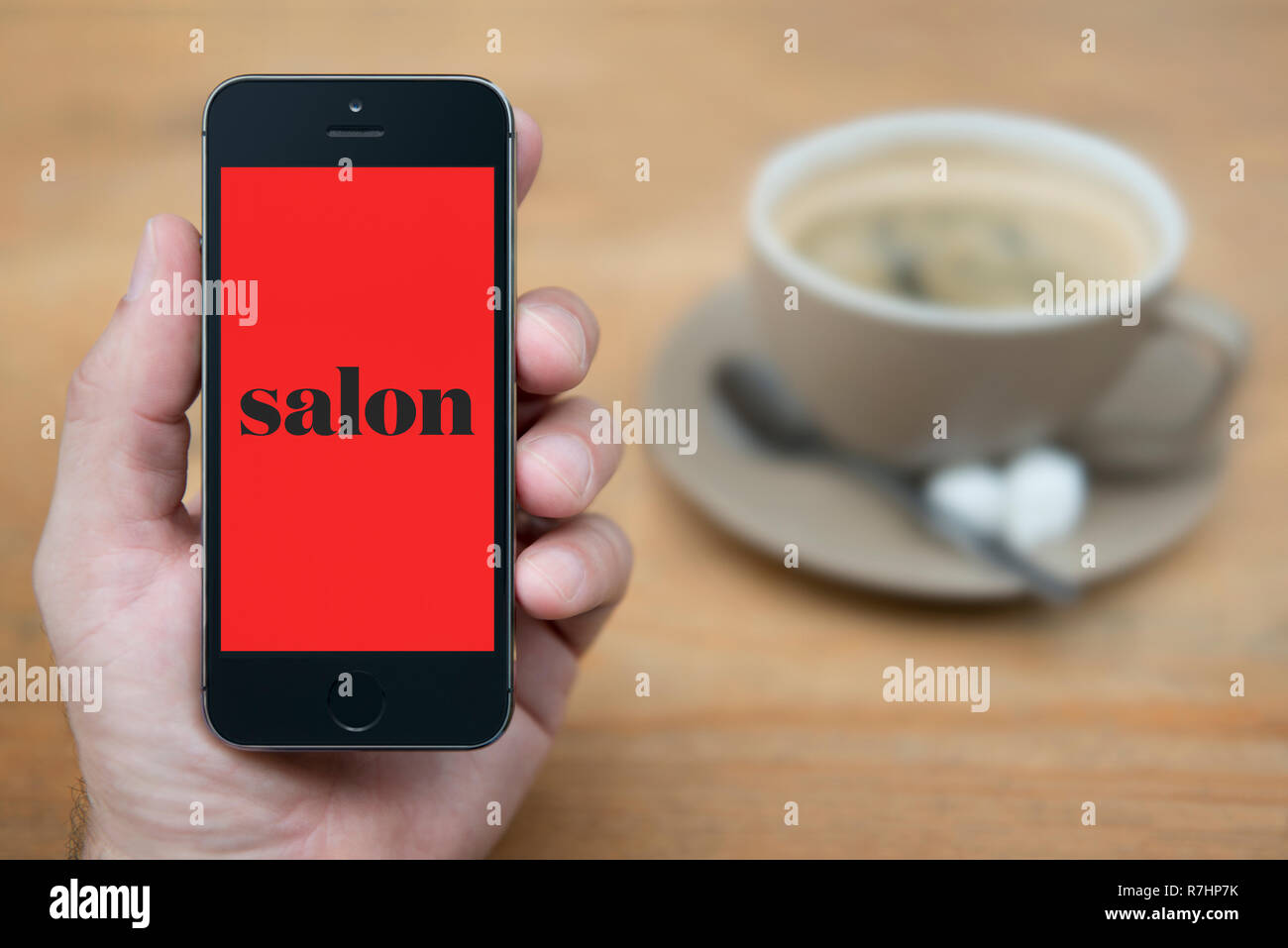 Ein Mann schaut auf seinem iPhone wird der Salon Logo (nur redaktionelle Nutzung). Stockfoto