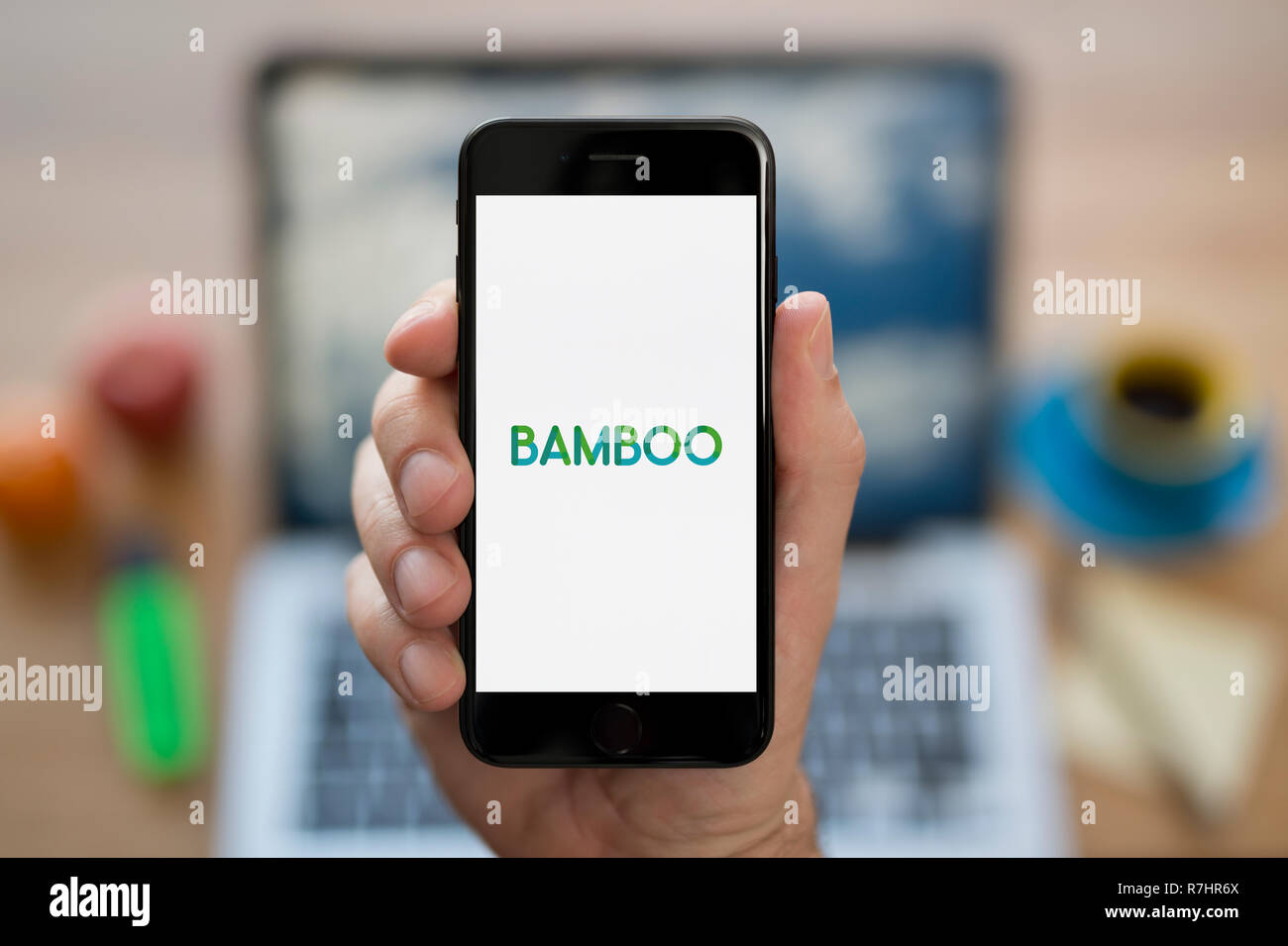 Ein Mann schaut auf seinem iPhone wird der Bambus Logo (nur redaktionelle Nutzung). Stockfoto