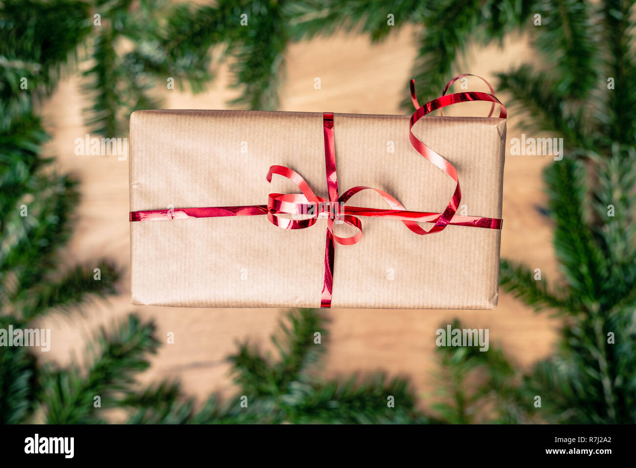 Weihnachten Geschenk auf Holzbrett mit Tanne. Red Ribbon auf Papier Geschenkbox. Top Detailansicht mit kopieren. Stockfoto
