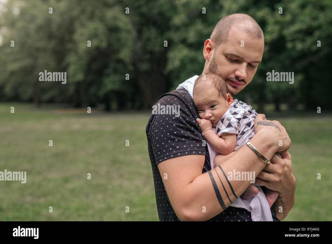 Liebevolle junge Vater außerhalb schaukelnd seine adorable Baby Boy Stockfoto