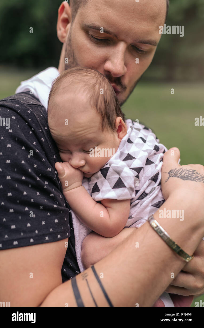 Pflege junger Vater außerhalb schaukelnd seine adorable Baby Boy Stockfoto