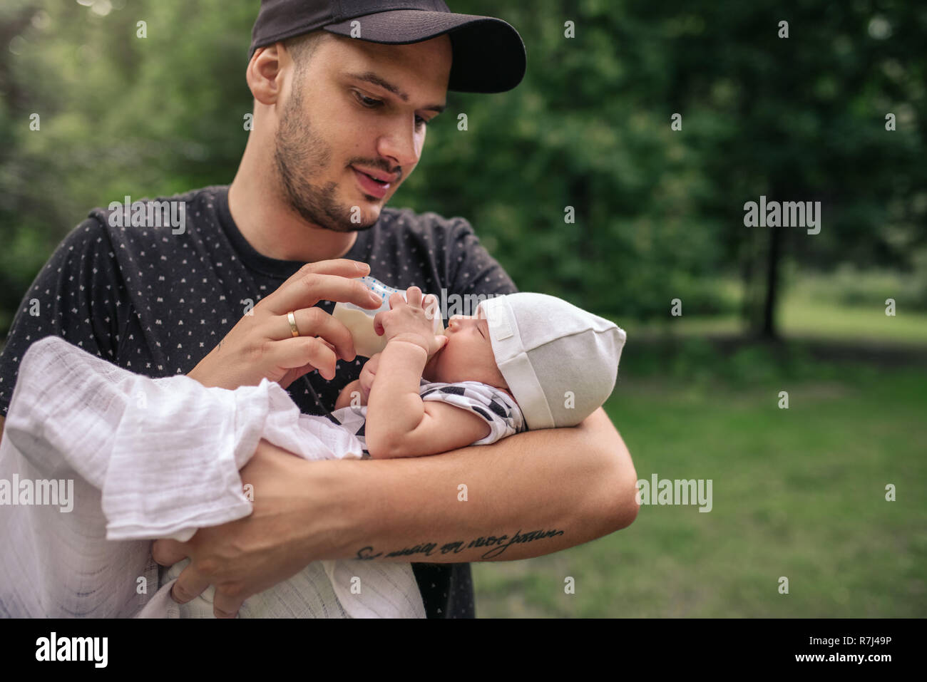 Vater draußen sein baby boy Füttern mit der Flasche Stockfoto
