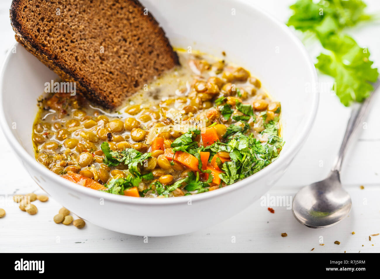 Hausgemachte vegan Linsensuppe mit Gemüse und cilantro, weiß Holz- Hintergrund. Indische vegetarische Küche. Stockfoto