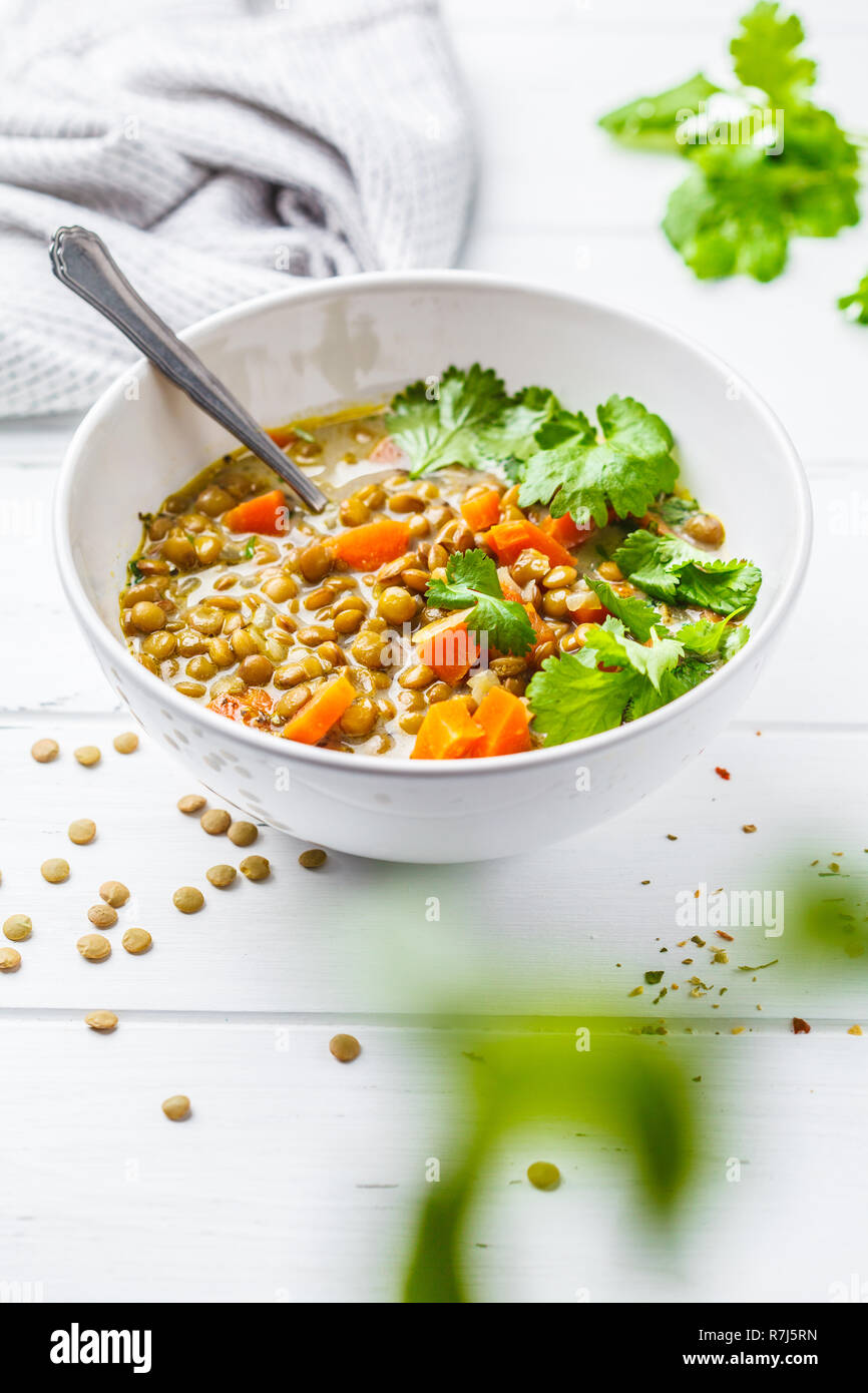 Hausgemachte vegan Linsensuppe mit Gemüse und cilantro, weiß Holz- Hintergrund. Indische vegetarische Küche. Stockfoto