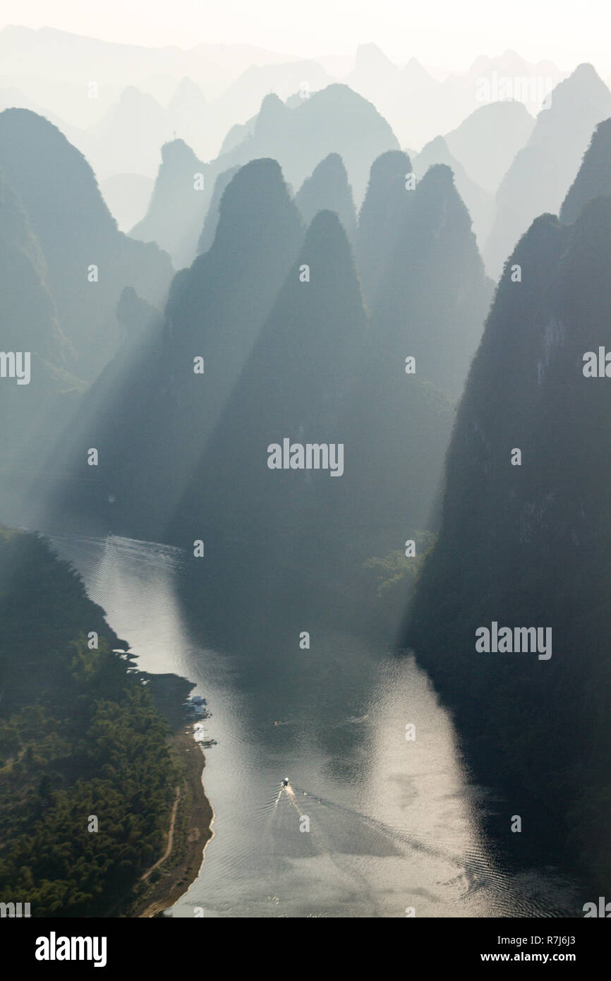 Vertikale Foto von Hügeln in Silhouette in der Sonnenaufgang über Li River ab Xianggong Mountain in der Nähe von Guilin, China gesehen. Sonnenstrahlen zwischen Hügeln glänzen. Stockfoto