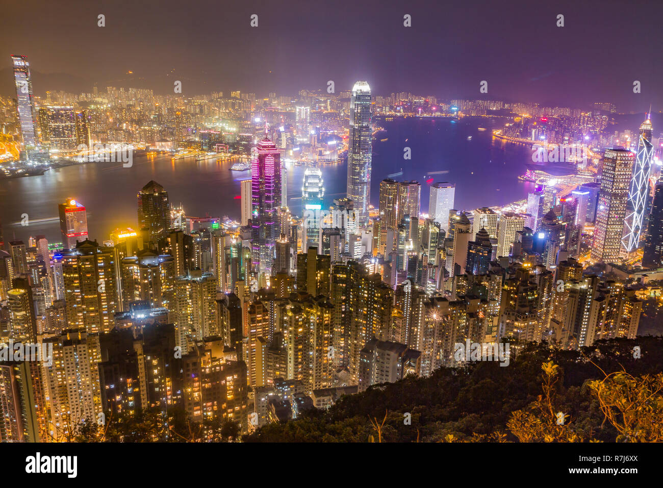 Hong Kong Skyline bei Nacht vom Victoria Peak gesehen. Beleuchtete Wolkenkratzer im Vordergrund, Hong Kong Hafen im Hintergrund. Stockfoto