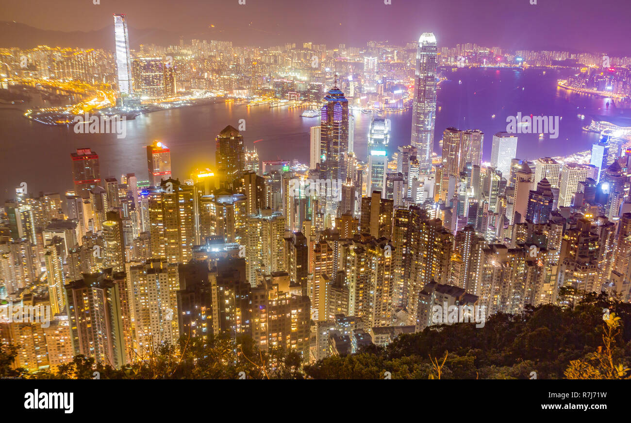 Hong Kong Skyline bei Nacht vom Victoria Peak gesehen. Beleuchtete Wolkenkratzer im Vordergrund, Hong Kong Hafen im Hintergrund. Stockfoto