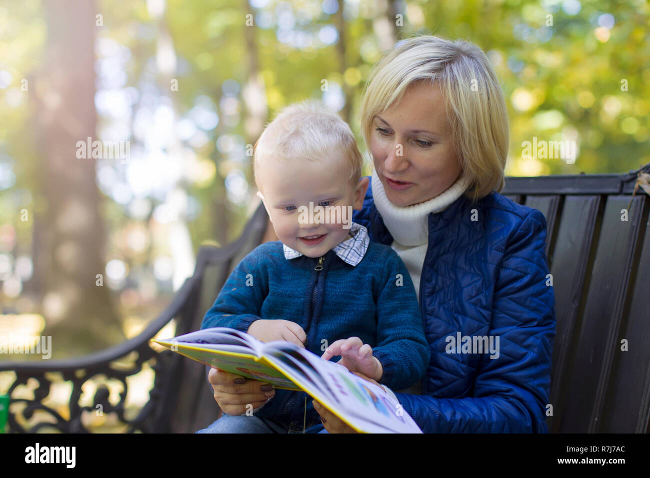 Mamma zu einem Kind liest ein Buch im Park spazieren. Ein Buch mit einem Kind Stockfoto