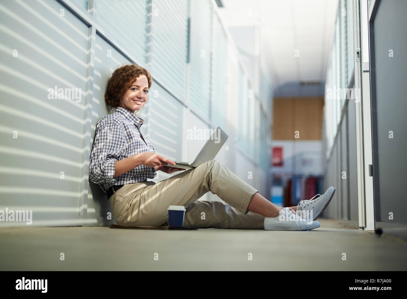 Freundliche attraktive Student Mädchen mit Laptop im Korridor Stockfoto