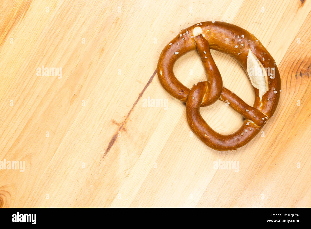 Ein deutscher Brezel auf einem typischen hölzernen Oktoberfest bierbank. Kopieren Sie Speicherplatz zur Verfügung. Stockfoto