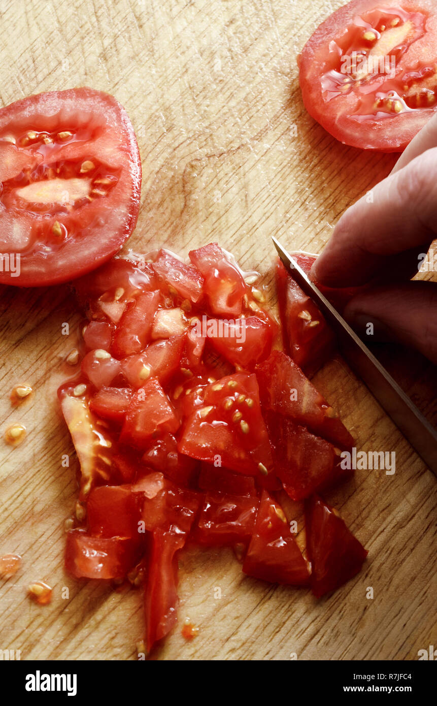 Overhead shot von Hand Messer zum Hacken und Schneiden saftigen, roten  rohen Salat Tomaten auf Holz Schneidebrett Stockfotografie - Alamy