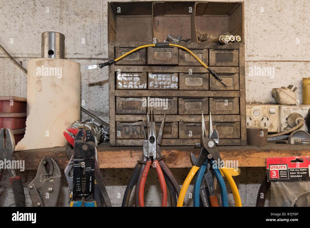 Ein alter Satz Teile Schubladen und Zange, Zinn-schnitte und Griffe hängen von Nägeln in einem Holz Regal in einer Werkstatt gefahren Stockfoto