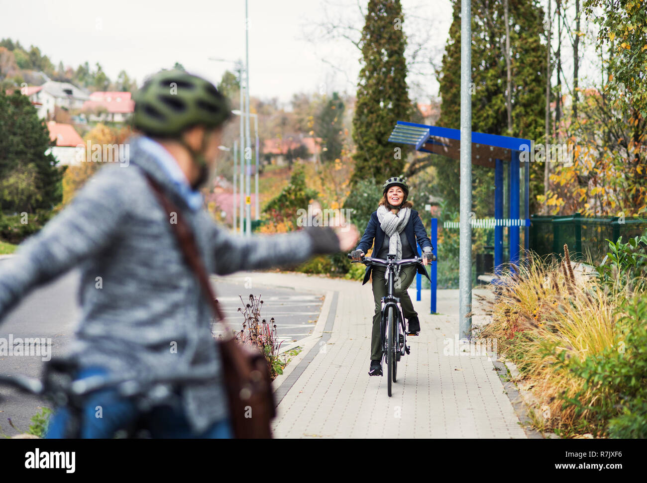 Eine aktive senior Paar mit elektrobikes Radfahren im Freien auf der Weg in die Stadt. Stockfoto