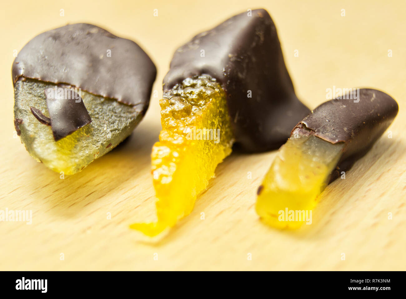 Leckere dunkle Schokolade Pralinen mit Birne, Orange und Ingwer auf einem hölzernen Schneidebrett Stockfoto