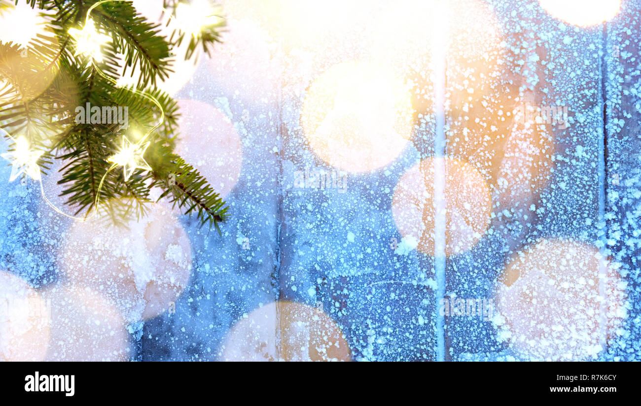 Frohe Weihnachten - Blau snowy Hintergrund und Tannenbaum Äste mit Feiertagen leuchtet Stockfoto
