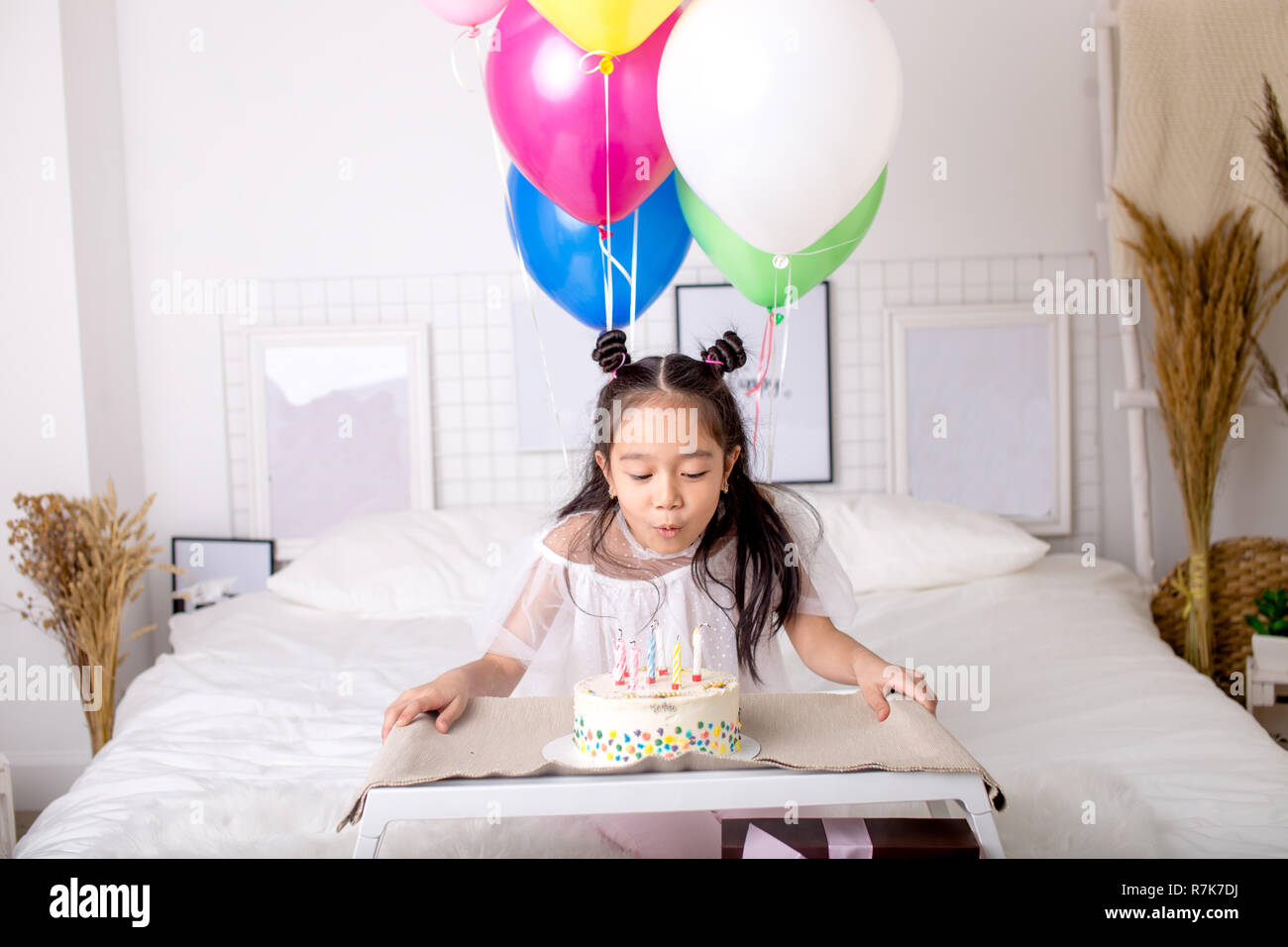 Kleine asiatische Mädchen bläst die Kerzen auf Kuchen und einen Wunsch. Stockfoto