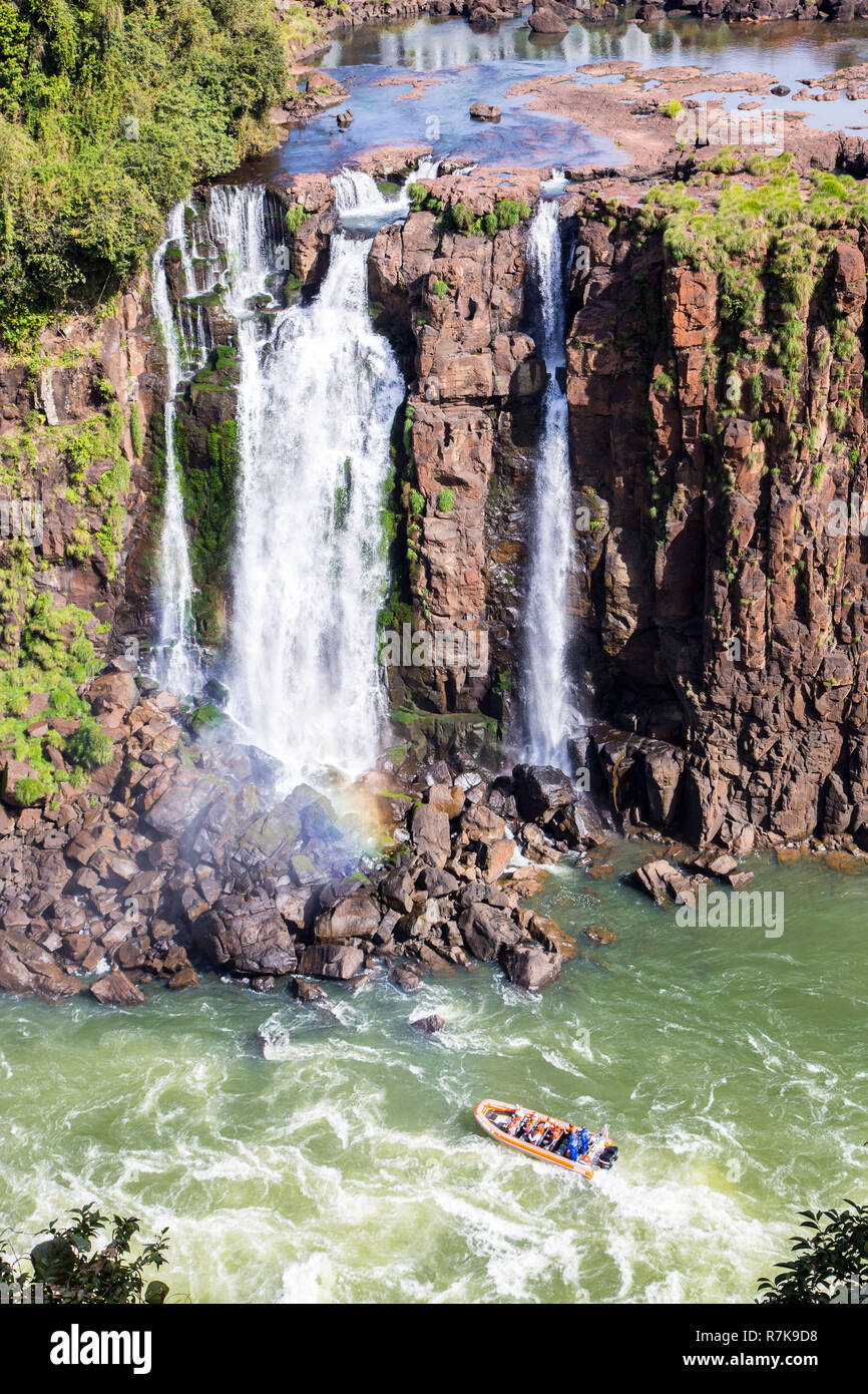 Boot mit Touristen unter dem Spritzwasser und Bächen der Iguazu Wasserfälle. Grenze zwischen Brasilien und Argentinien. Iguazu Fälle mit dem Boot erleben Stockfoto Boot mit Touristen unter dem Spritzwasser und Bächen der Iguazu Wasserfälle. Grenze zwischen Brasilien und Argentinien. Iguazu Fälle mit dem Boot erleben Stockfoto