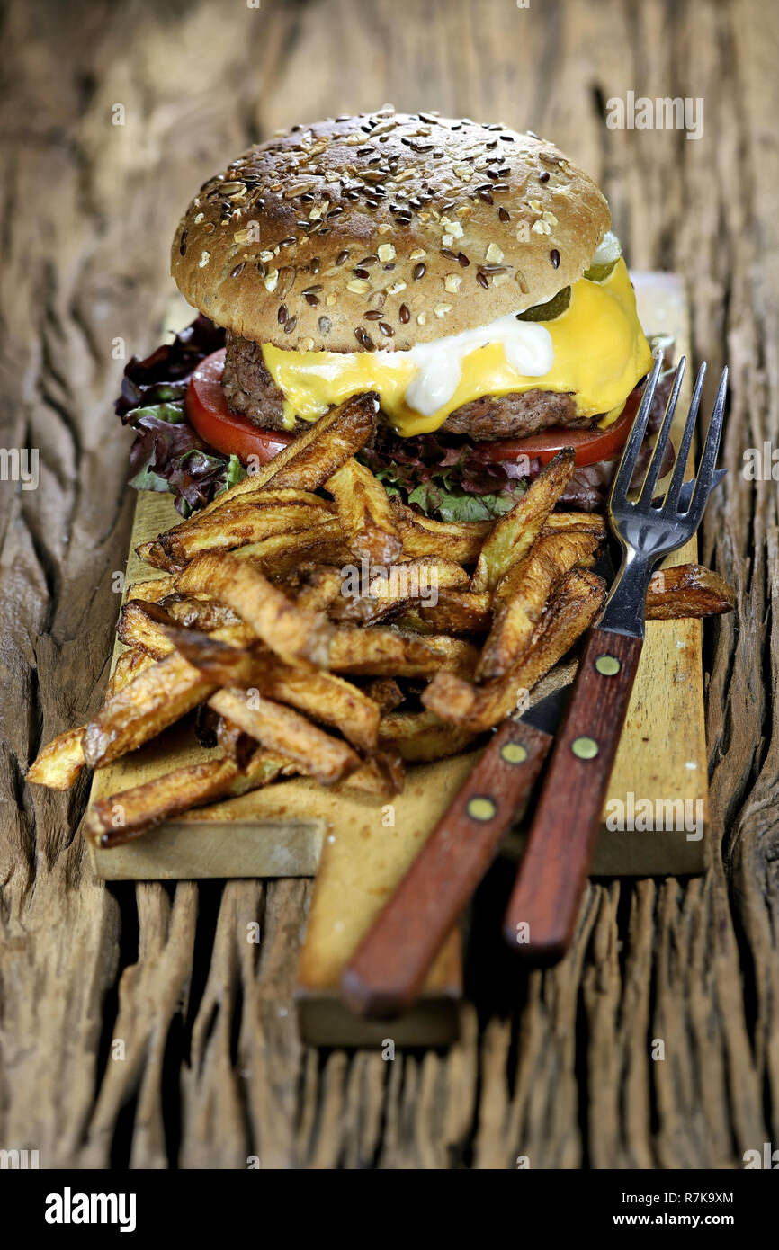 Selbstgemachte Cheeseburger und Pommes frites auf rustikalen hölzernen Hintergrund Stockfoto
