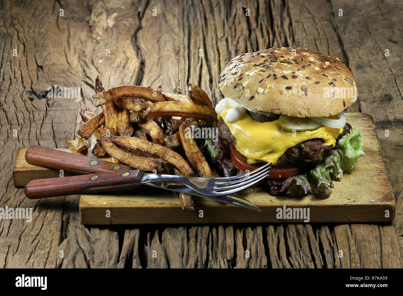 Selbstgemachte Cheeseburger und Pommes frites auf rustikalen hölzernen Hintergrund Stockfoto